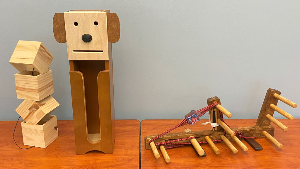 Woodworking projects on a table: an LED lamp, a toilet paper holder, and an Inkle loom.