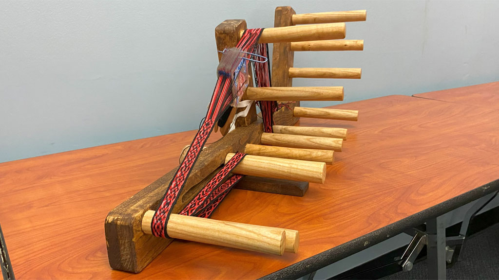 A hand-made Inkle loom with a weaved band by Laura Rhodes.